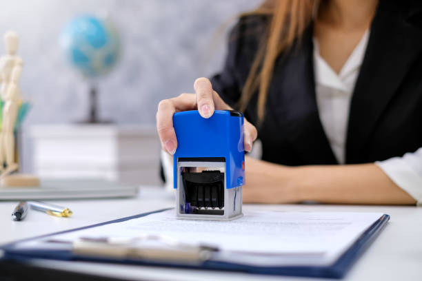 Close up of businesswoman hands approve documents stamp at the office.